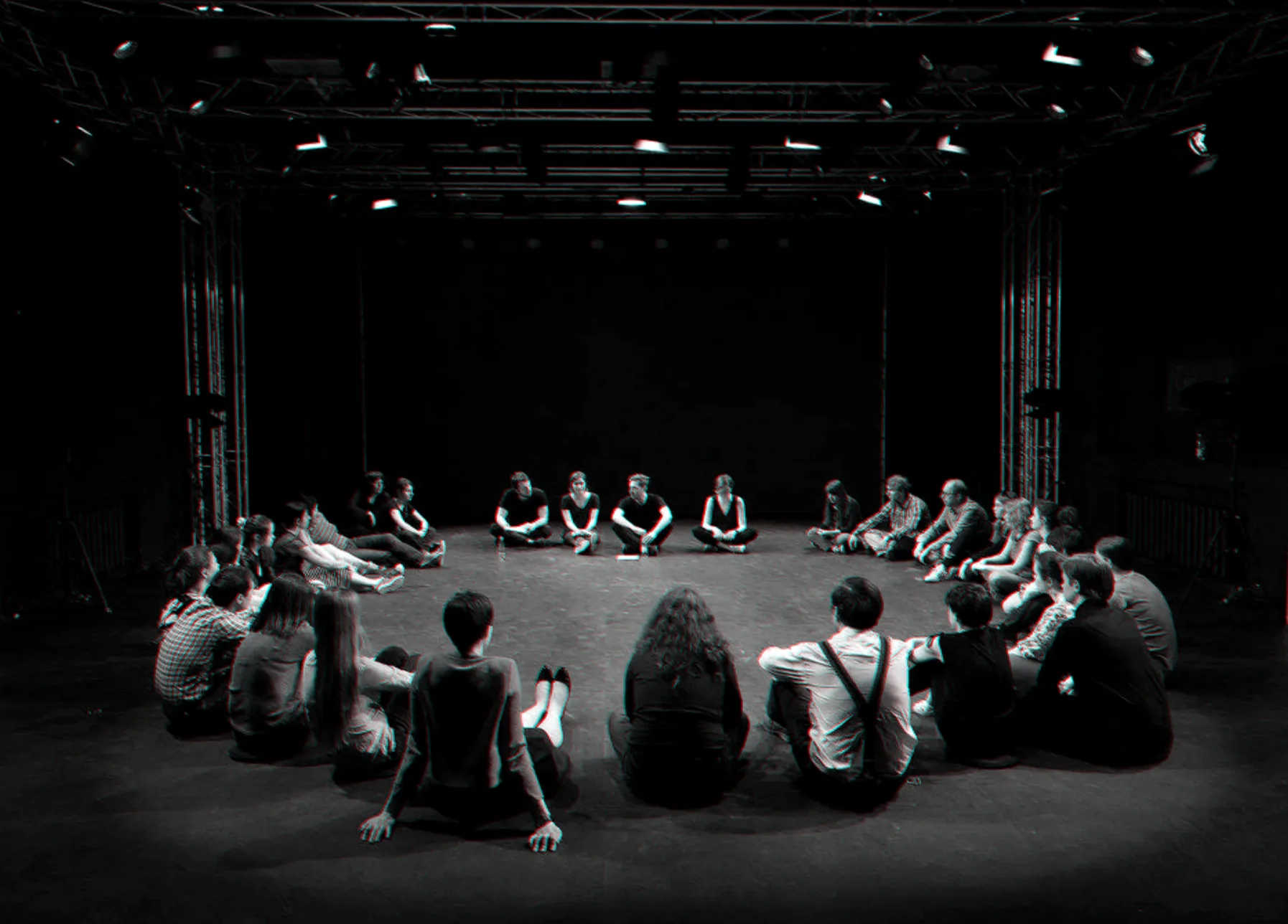 A wide circle of participants on a dark stage