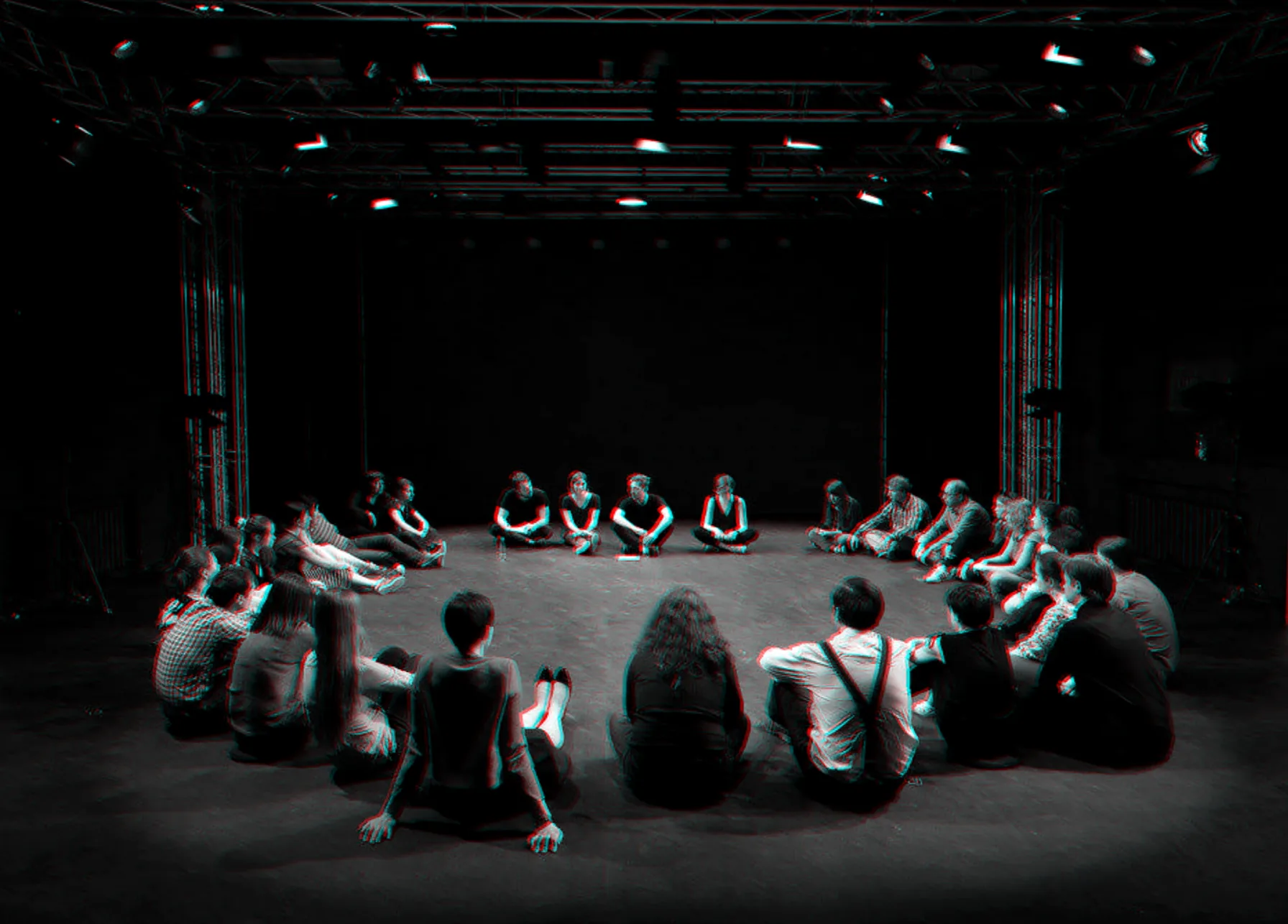 A wide circle of participants on a dark stage