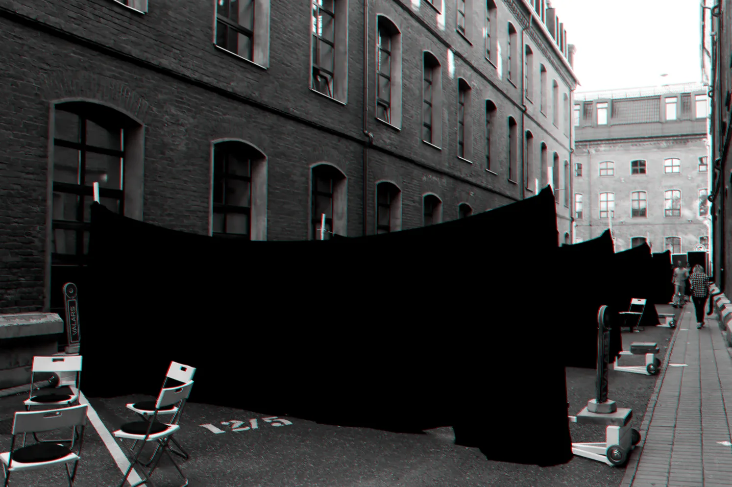 Black curtains stretched across a brick courtyard